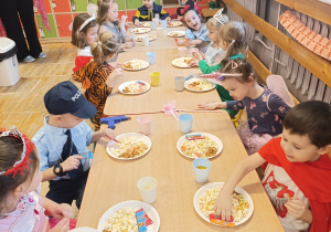 Dzieci siedzą przy stole podczas słodkiego poczęstunku