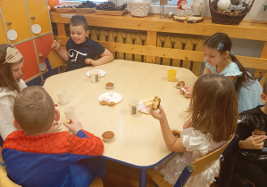 Dzieci z Grupy Odkrywcy jedzą słodkie przekąski.