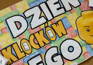 Zdjęcie przedstawia dekorację na tablicy z napisem Dzień Klocków LEGO oraz ludzika Lego