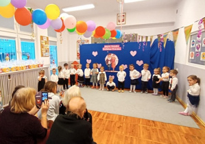 Dziadkowie oglądający wnuczęta recytujące wiersz.