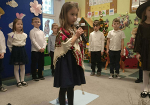 Dziewczynka trzyma mikrofon w rękach.