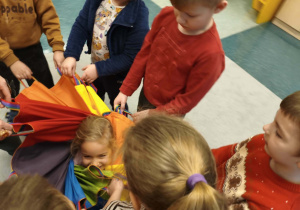 Dzieci bawią się kolorową chustą animacyjną.