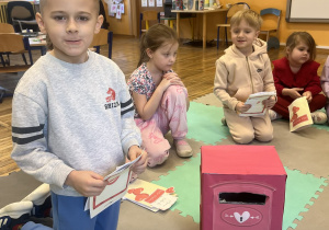 Chłopiec wkłada kartkę walentynkową do skrzynki na listy.