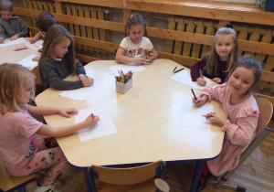 Zdjęcie przedstawia dzieci, rysujące poznane przez siebie wzory geometryczne, figury geometryczne, cyfry i znaki matematyczne.