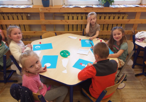 Zdjęcie przedstawia dzieci, wykonujące pracę plastyczną z bałwankiem.