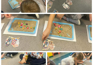 Dzieci z tacek z piaskiem wyszukują obrazki z postaciami bajkowymi.
