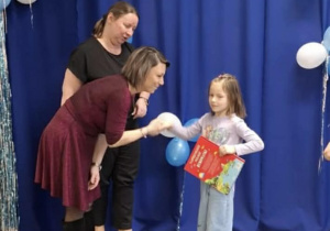 Dziewczynka z grupy Motylki otrzymuje dyplom oraz nagrodę za udział w konkursie.