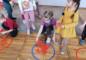 Dziewczynka wkłada do obręczy tyle serduszek ile wskazuje cyfra