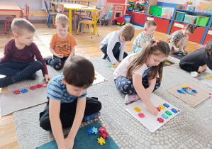 Dzieci układają tyle klocków, jaką cyfrę pokazał im nauczyciel. Przeliczają klocki