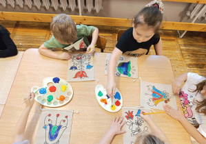 Dzieci ozdabiają swoje torebki malując folkowe wzory.