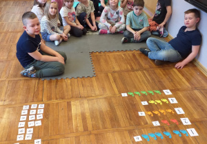 Zdjęcie przedstawia dzieci, które posegregowały dinozaury ze względu na kolor.