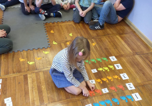 Zdjęcie przedstawia dziecko wykonujące działanie dodawania.