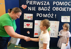 Pani wicedyrektor gratuluje chłopcowi i wręcza mu dyplom