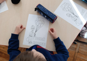 Chłopcy z grupy „Misie” przygotowują laurkę dla swoich koleżanek.