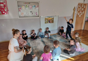 Dzieci siedzą na dywanie.