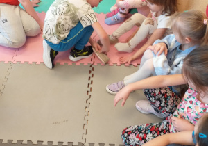 Chłopiec przymierza pantofelka jednej z dziewczynek.