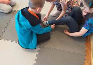 Chłopiec przymierza pantofelka jednej z dziewczynek.