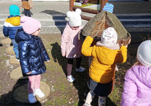 Przedszkolaki bawią się na dworze w przedszkolnym ogródku.