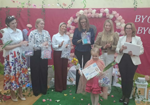 Dziewczynka pozuje do pamiątkowego zdjęcia z jury.