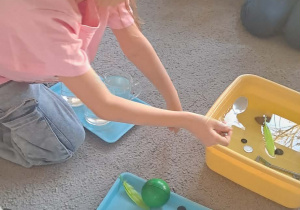 Dziewczynka wrzuca łyżeczkę do wody.