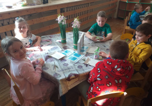 Dzieci pakują mydełko do pięknie przyozdobionych torebeczek.