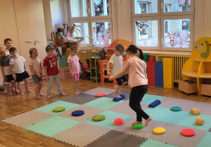 Dzieci chodzą gołymi stopami po ścieżce sensorycznej.