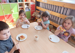 Dzieci jedzą gofry z dżemem.