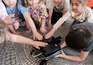 Dzieci oglądają gofrownicę i poznają zasady bezpiecznego korzystania z urządzenia elektrycznego.