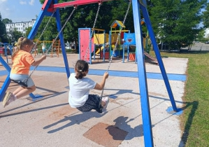 Dwie dziewczynki huśtające się na huśtawkach na placu zabaw
