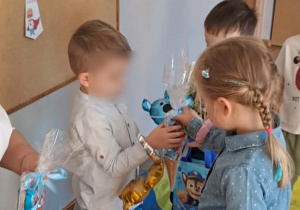 Dziewczynka wręcza chłopcom upominki.