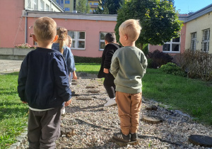 Dzieci bawią się na ścieżce sensorycznej w ogrodzie przedszkolnym.