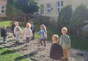 Dzieci korzystają ze ścieżki sensorycznej znajdującej się w ogrodzie przedszkolnym.