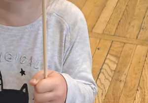 Dziecko wykonuje ćwiczenia oddechowe, dmuchając na wiatraczek.