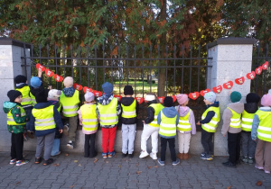 Dzieci z grupy Motylki wieszają łańcuch serc przy pomniku Jana Pawła II.