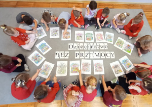 Przedszkolaki z grupy Biedronki siedzą dookoła kolorowanek i napisu Dzieciństwo bez Przemocy.
