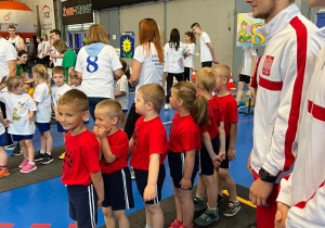 Drużyna przedszkolaków czeka uśmiechnięta przy linii startu na rozpoczęcie rozgrywki.