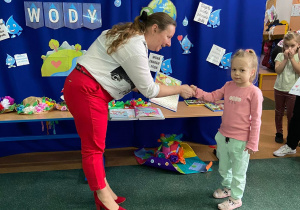 Zdjęcie przedstawia dziewczynkę, która otrzymuje nagrodę