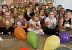 Dzieci z grupy Smerfy pozują do zdjęcia w medalach z okazji Dnia Przedszkolaka.